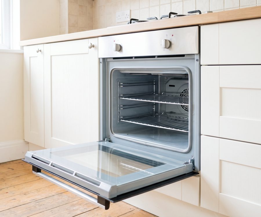 An open oven with clean enamel sides, clear inner door glass and wire shelves back in place