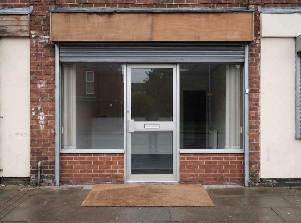 A shop and office frontage with clean glazing and a swept paved forecourt, early in the morning