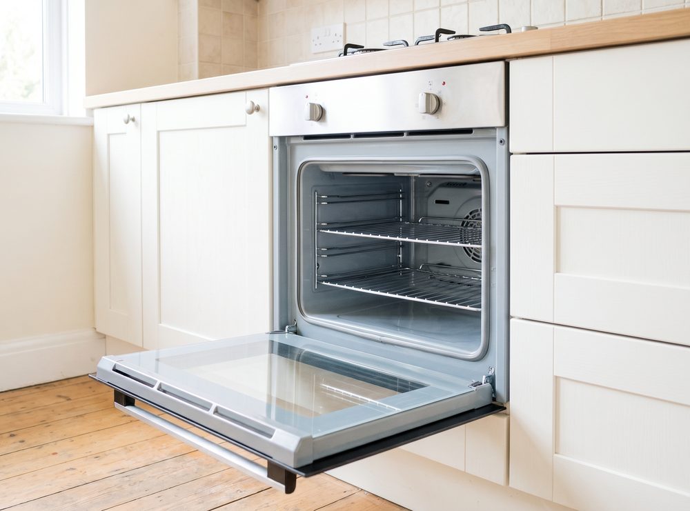 An open oven with clean enamel sides, clear inner door glass and wire shelves back in place