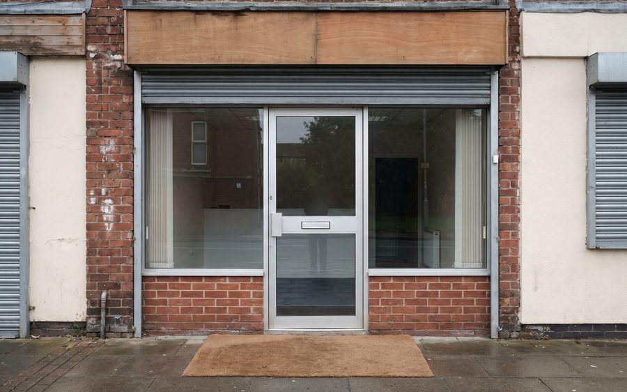 A shop and office frontage with clean glazing and a swept paved forecourt, early in the morning