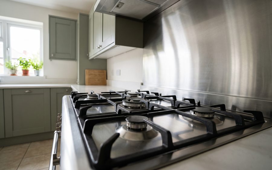 A stainless gas hob with cast iron pan supports, clean and reflecting light softly